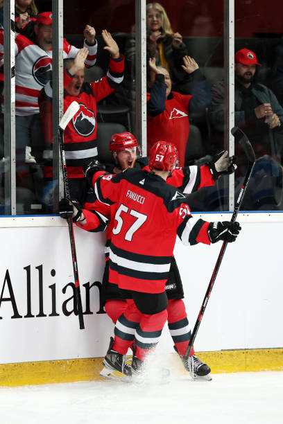 Excited Fans and Players Celebrate Together Red team hockey players celebrate a goal near the glass as ecstatic fans in matching jerseys cheer and raise their arms in joy, showcasing the shared enthusiasm of players and supporters. red hockey jersey stock pictures, royalty-free photos & images