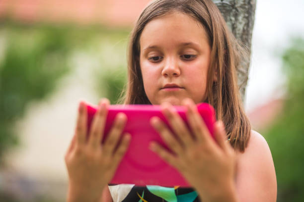 istock Young girl using tablet outdoors in a green park 2185358757
