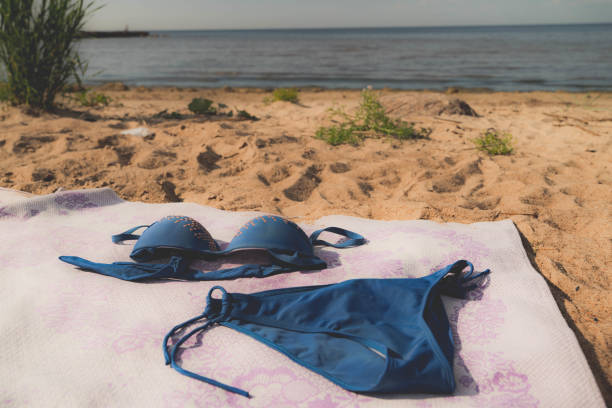 A blue bikini is laid on a sandy beach near the water.