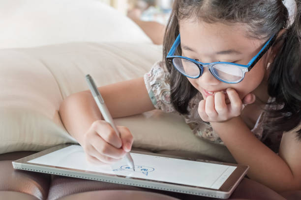 istock School child girl kid using internet online learning on mobile tablet reading looking at digital screen for educational study for Childrenâs Eye Health and Safety Month and Blue Light Awareness Day 2185364021