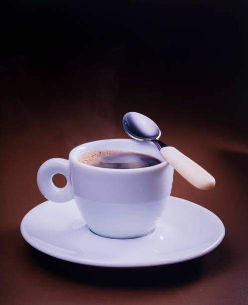 cup of coffee with spoon on dark brown background, close-up