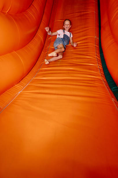 istock Girl moving down steep soft orange slide 2185368402
