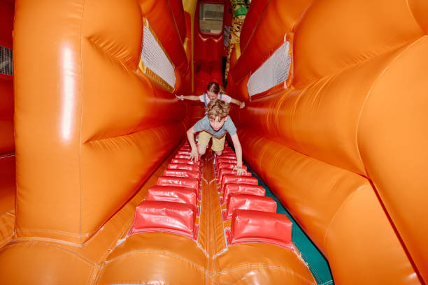 istock Kids climbing soft orange leather tunnel 2185368425