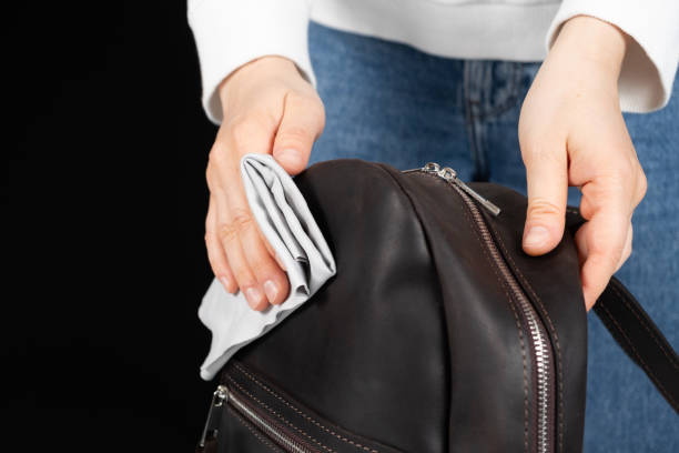 Cleaning the surface of a leather backpack with a cloth. Caring for leather accessories. stock photo
