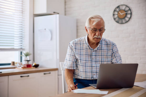 istock Senior man paying bills online while using laptop at home. 2185368972