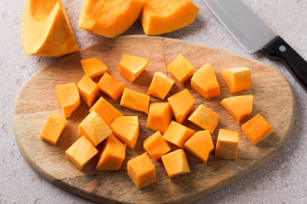 istock Pumpkin cut into pieces on a wooden board on a beige textured background 2185371573