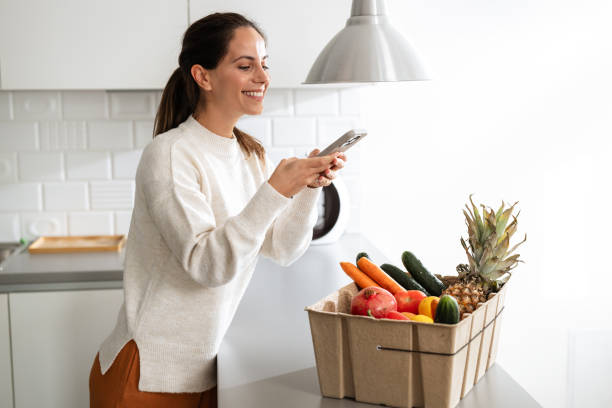 istock Woman photographing fresh produce in modern kitchen setting 2185373761