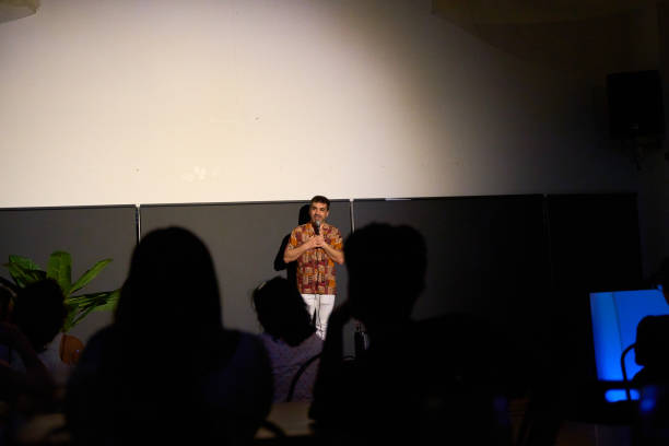 istock Male performer delivering a monologue on stage in a dimly lit theater with audience 2185375244