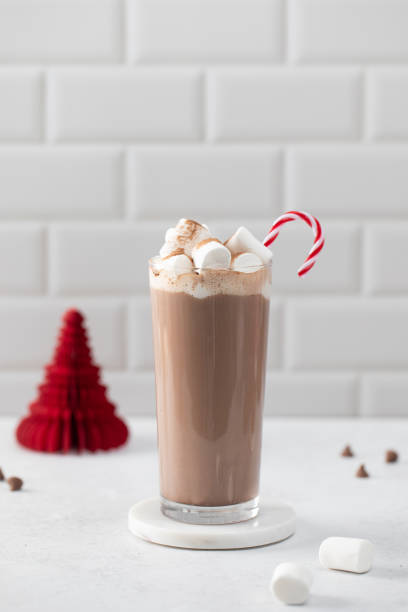 Candy cane into glass with cocoa on white table