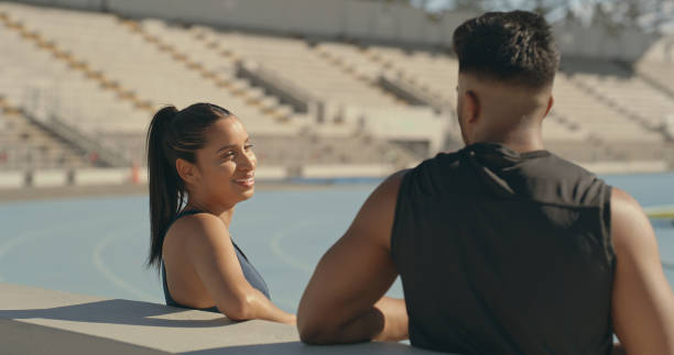 istock Two young athletes chatting while taking a break from training at a stadium. Man and woman or couple, talking after playing sport outdoors 2185376349