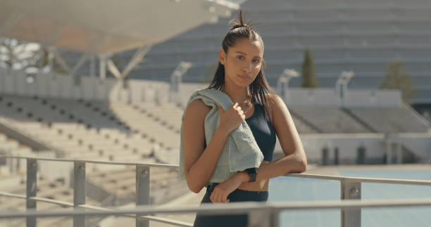 istock A serious female athlete taking a break after exercise at a stadium and looking at the camera. Portrait of a confident young woman playing sport outdoors 2185376375