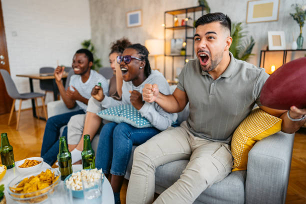 istock Group Of Friends Drinking Beer And Having Snacks While Watching A Rugby Game Together In The Living Room 2185377986