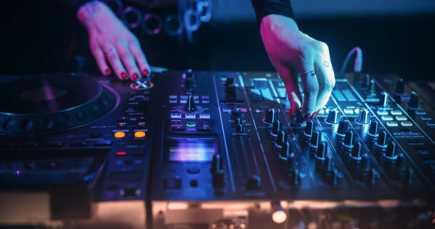 istock Female DJ Skillfully Mixing Tracks on Turntables, Captured From an Overhead Angle. Lighting Adds to Concert Atmosphere, Highlighting Precise Control Over the Professional DJ Equipment. 2185379071