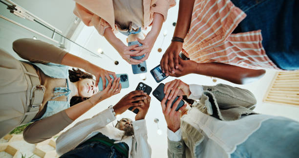istock People, circle and phones for university learning, online and teamwork in education on campus. Students, low angle and huddle for project solidarity in college, collaboration and united studying 2185379354