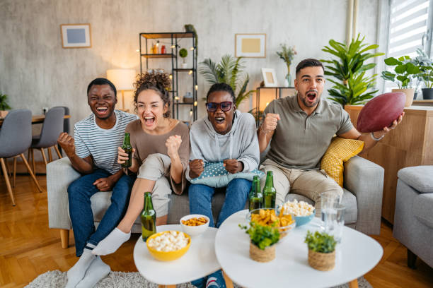 istock Group Of Friends Drinking Beer And Having Snacks While Watching A Rugby Game Together In The Living Room 2185379419