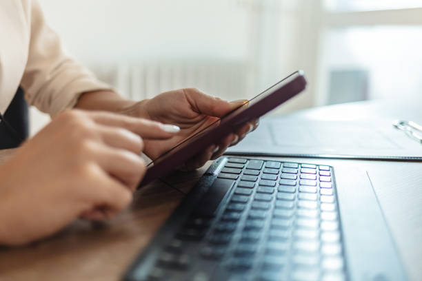 istock Young woman using mobile phone and working at home office with headphones on. 2185381131