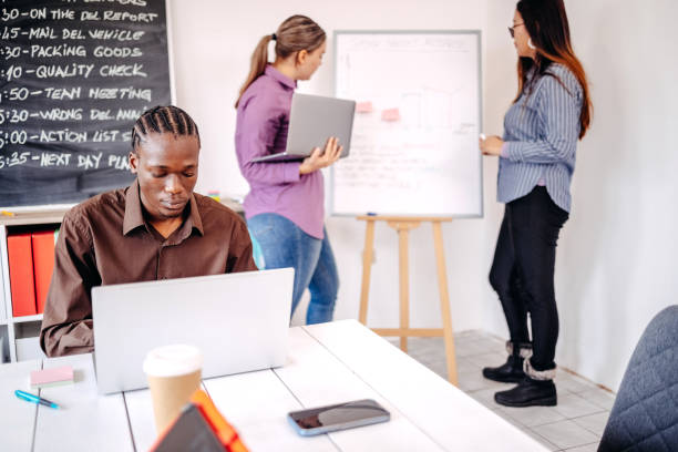 istock Small group of people collaborating at meeting room while standing in front of white board and using laptops for planning 2185381300