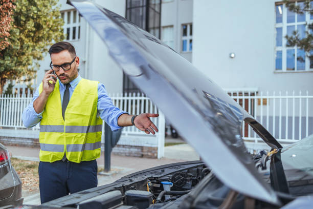 istock Man in Safety Vest Inspecting Car Engine and Making Call 2185383792