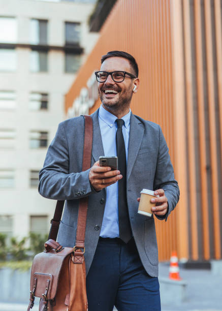 istock Confident Businessman Walking Downtown with Coffee and Smartphone 2185384038