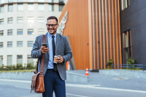 istock Confident Businessman Checking Phone While Walking Outside Office Building 2185384045