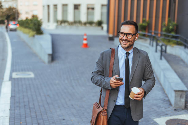 istock Confident Businessman Walking Outside with Coffee and Smartphone 2185384159