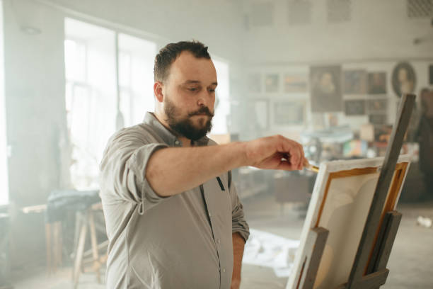 istock Male artist priming a canvas in his creative studio 2185384258
