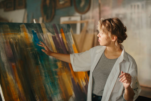 istock A woman painter using her hands to craft an abstract masterpiece on a large canvas. 2185387119