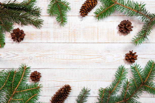 istock Christmas background - fir branches and pine cones on a white wood table. Flat layout, top view composition border with copy space 2185387254
