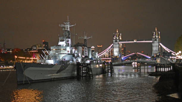 London, United Kingdom, November 14, 2024. HMS Belfast warship museum to Tower Bridge from Southbank of the River Thames. Winter night outdoors in the capital city