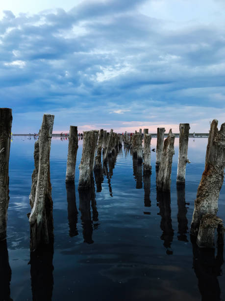istock Old wooden pier extending into tranquil reflective water 2185391890