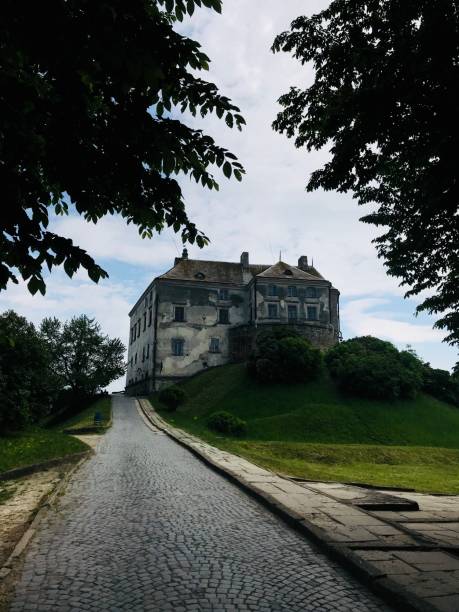 istock Historic castle with cobblestone path surrounded by lush greenery. Olesko, Ukraine. 2185393726