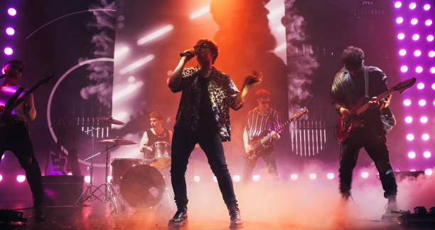 istock Talented Rock Band Performing a Live Set on an Indoors Stage with Visual Art Display. Young Musicians Playing a Concert at a Festival, Singing Hard Rock Songs at an Indie Event. Zoom On a Lead Singer 2185398512