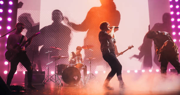 istock Talented Rock Band Performing a Live Set on an Indoors Stage with Visual Art Display. Young Musicians Playing a Concert at a Festival, Singing Hard Rock Songs at an Indie Event. Zoom On a Lead Singer 2185398539