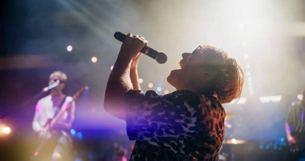 istock Professional Rock Musicians Performing Under Falling Confetti on Festival Stage, Playing Popular Rock Tracks in Front of a Crowded Concert Arena. Electrifying Performance at an Indoors Festival 2185399215
