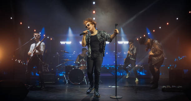 istock Professional Rock Musicians Performing Under Falling Confetti on Festival Stage, Playing Popular Rock Tracks in Front of a Crowded Concert Arena. Electrifying Performance at an Indoors Festival 2185399597