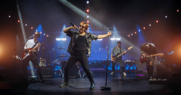 istock Professional Rock Musicians Performing Under Falling Confetti on Festival Stage, Playing Popular Rock Tracks in Front of a Crowded Concert Arena. Electrifying Performance at an Indoors Festival 2185399622