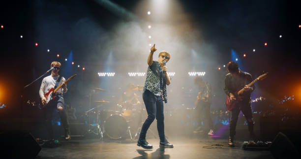istock Professional Rock Musicians Performing Under Falling Confetti on Festival Stage, Playing Popular Rock Tracks in Front of a Crowded Concert Arena. Electrifying Performance at an Indoors Festival 2185399707