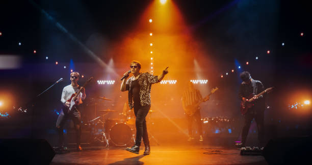 istock Professional Rock Musicians Performing Under Falling Confetti on Festival Stage, Playing Popular Rock Tracks in Front of a Crowded Concert Arena. Electrifying Performance at an Indoors Festival 2185399740