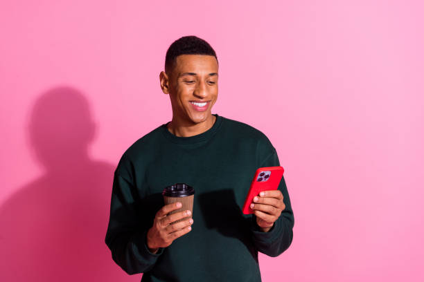 istock Photo of funky cool guy dressed pullover enjoy coffee writing sms modern device emtpy space isolated pink color background 2185399795