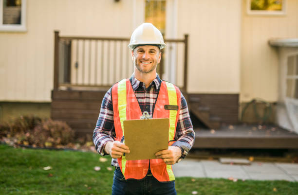 man with hard hat standing infront of a house