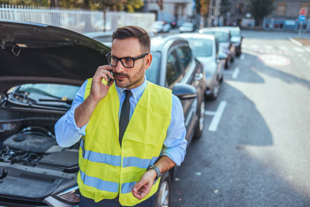istock Man in Safety Vest Making Phone Call by Broken Down Car 2185403598