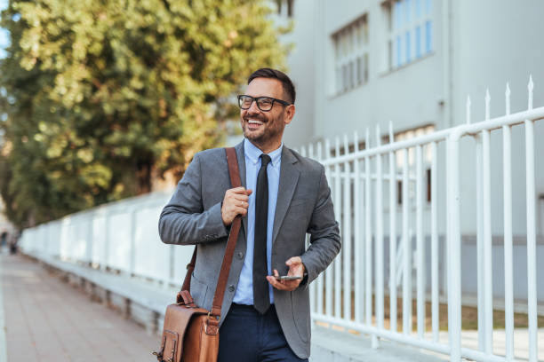 istock Confident Businessman Walking Outdoors with Briefcase and Phone 2185403624