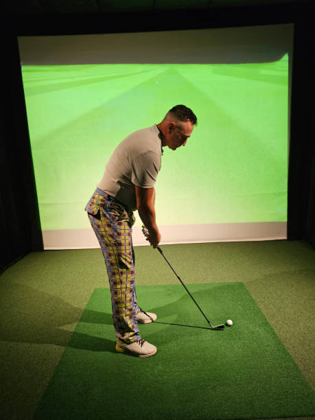 Golf enthusiast practicing his swing indoors with a virtual simulation in a recreational area concept