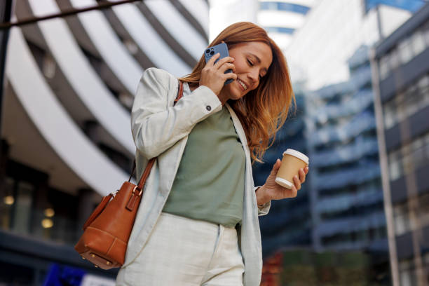 istock Woman on phone with coffee cup strolling in modern city setting 2185404494