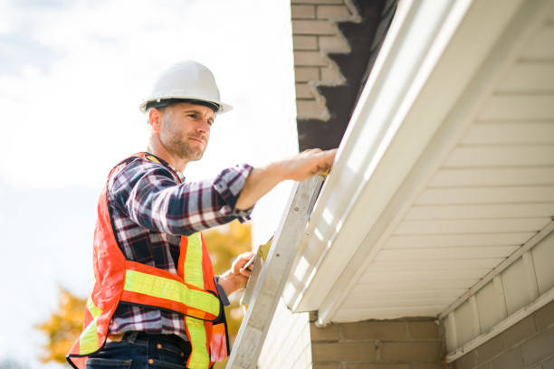 man with hard hat standing on steps inspecting house roof stock photo