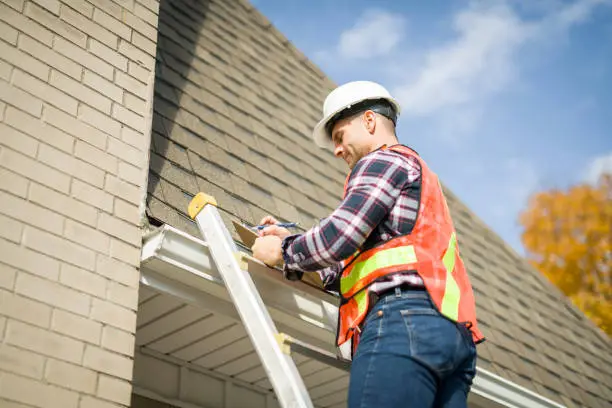 Inspector examining roof shingles