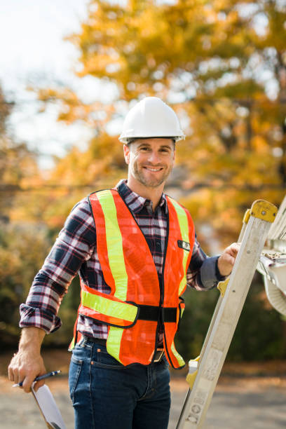 istock man with hard hat standing on steps inspecting house roof 2185404730