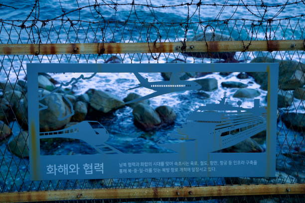 Sokcho City, South Korea - November 3rd, 2024: A detailed metal cutout in a barbed wire fence along the Oeongchi Sea Fragrance Trail showcases transportation motifs, with the East Sea waves crashing below.