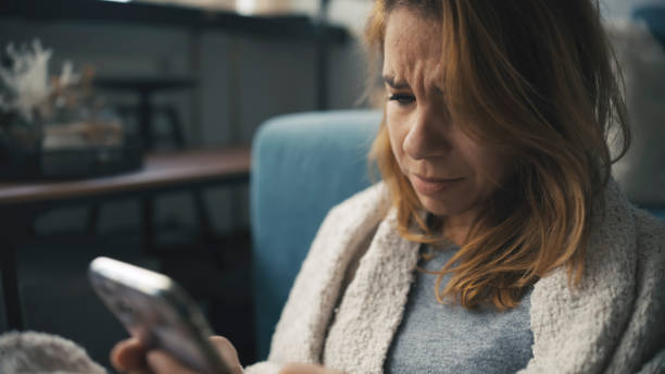 istock Distressed Female Engrossed in Smartphone at Home 2185407218