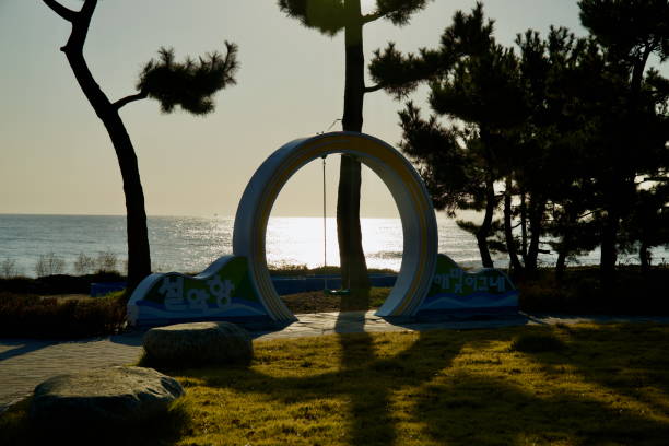 Sokcho, South Korea - November 3rd, 2024: A charming swing set within a circular frame at Seorak Sunrise Park, offering serene morning views of the East Sea as the sun reflects over calm waters.